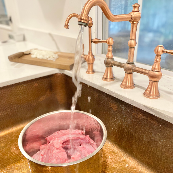 rabbit carcass in pot with water in a sink